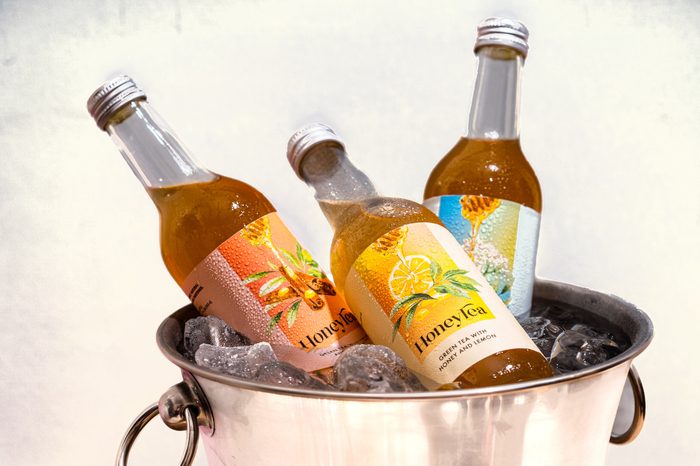 Bottles of HoneyTea chilling in a bucket of ice against a terracotta wall
